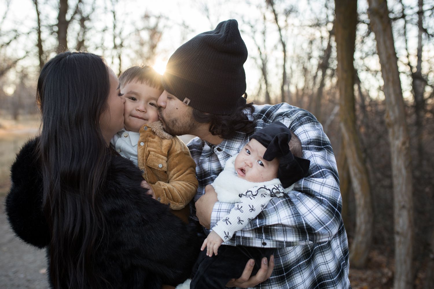 Parents snuggling their two young children at Reid Merrill Park in Eagle, Idaho during golden winter light.