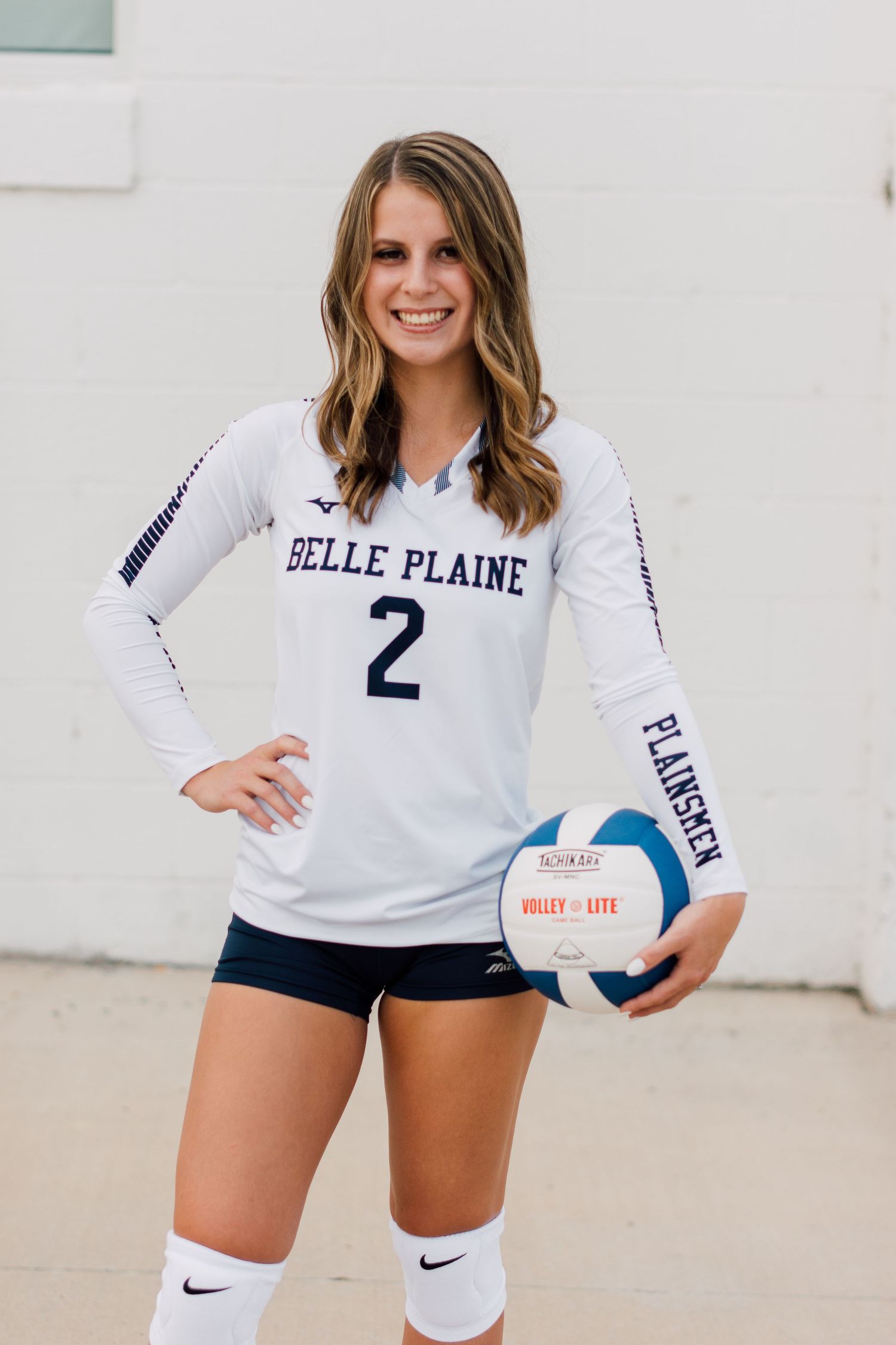 Volleyball player poses in white uniform with number 2 jersey against white background.