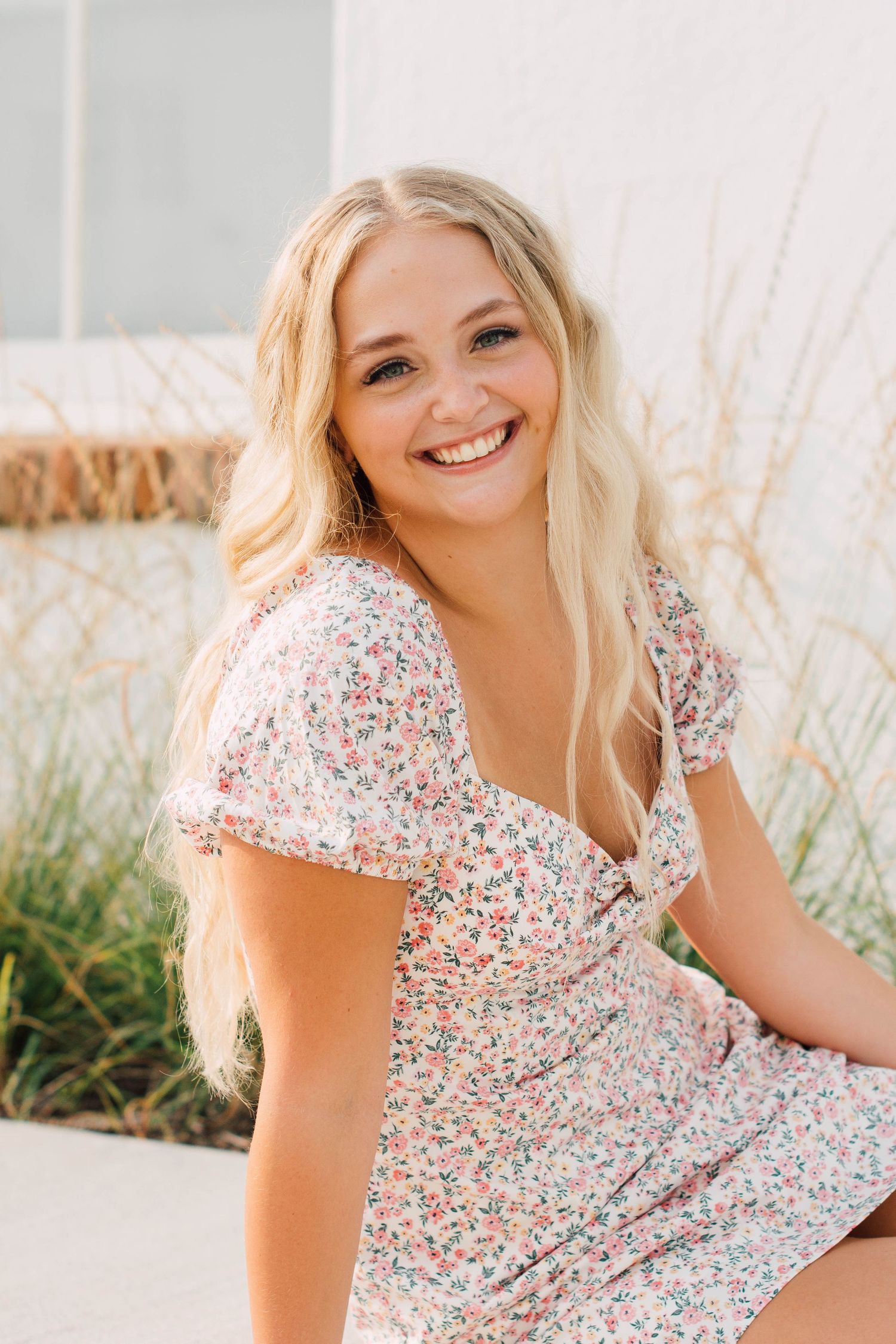 Casual spring portraits in floral print dress against natural coastal backdrop.