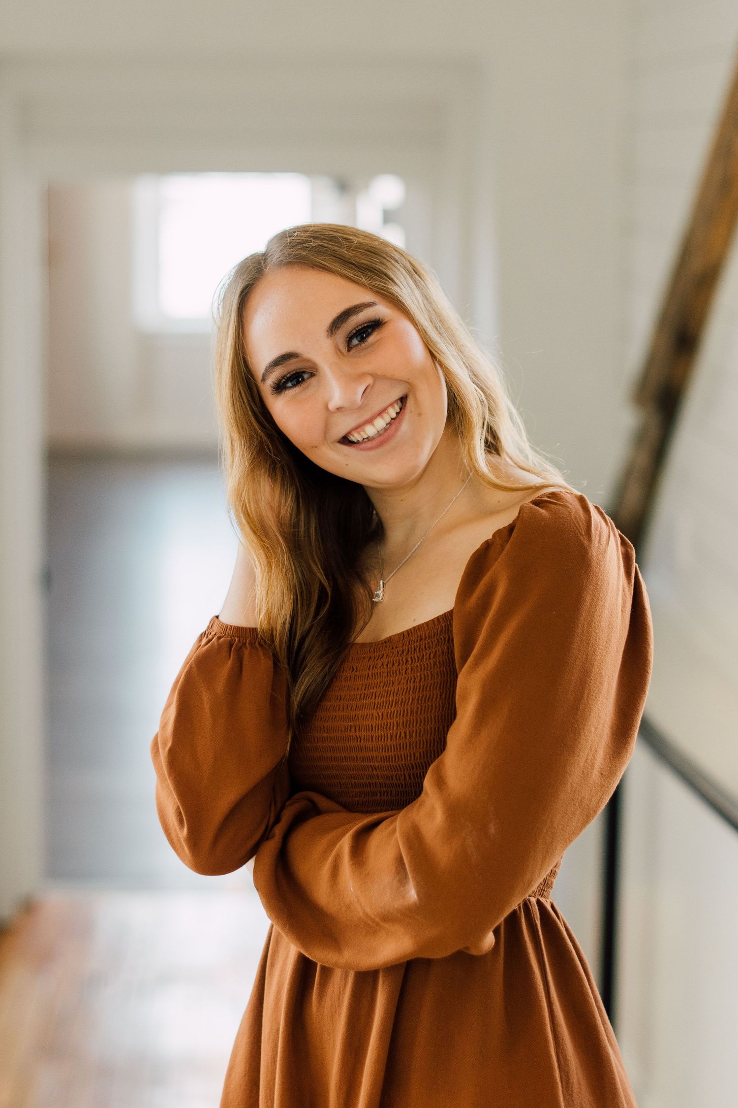 Indoor portrait series showing joyful expressions in a rust-colored sweater.
