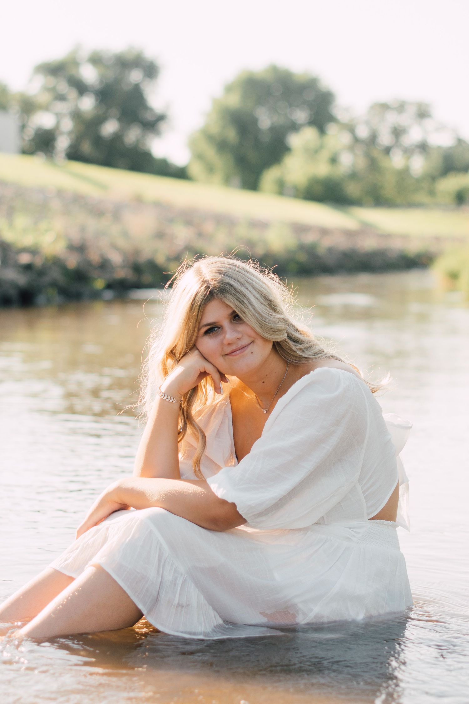 Ethereal water photoshoot in a flowing white dress during golden hour.