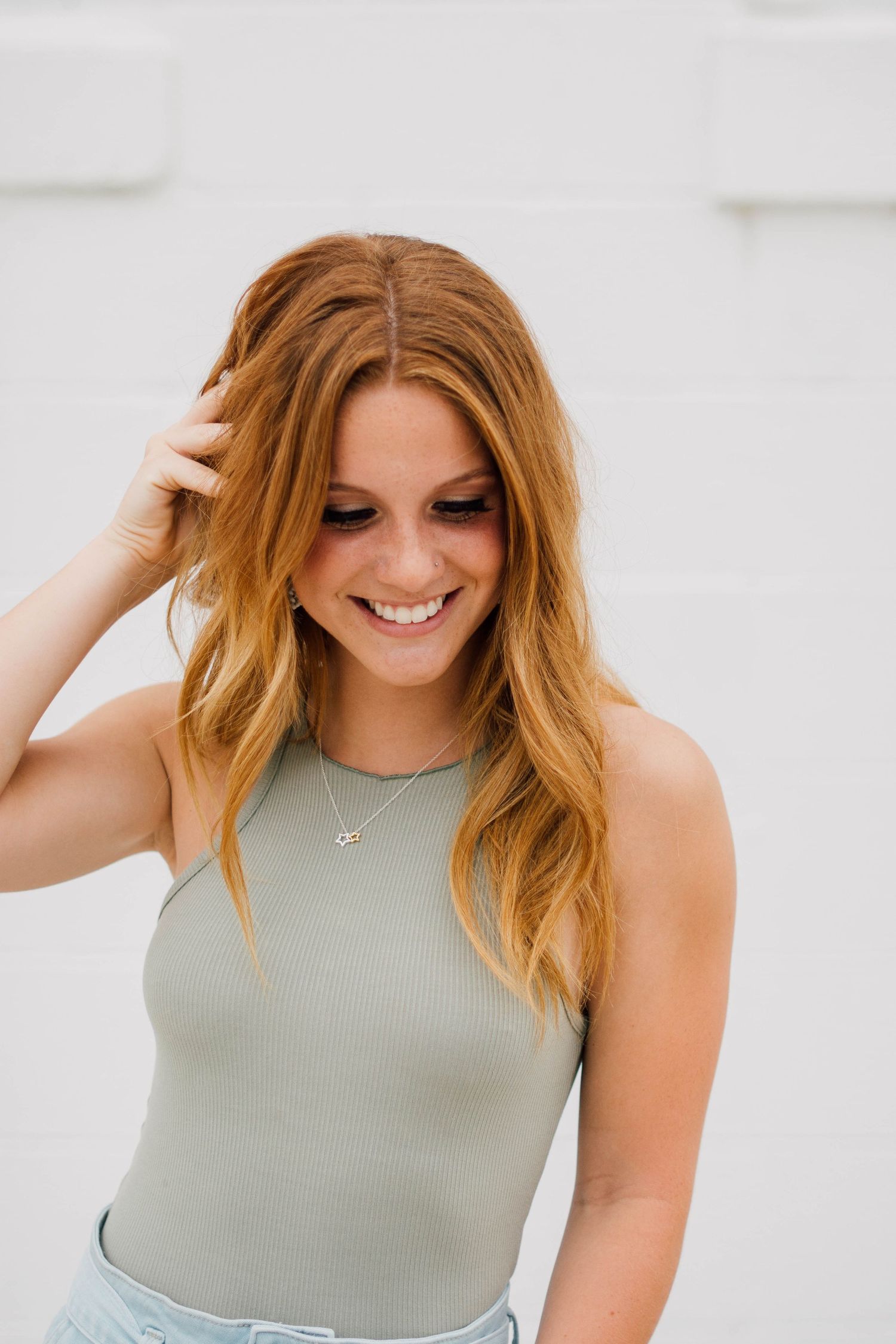 Studio portraits with natural hair styling and sage green tank top against white backdrop.