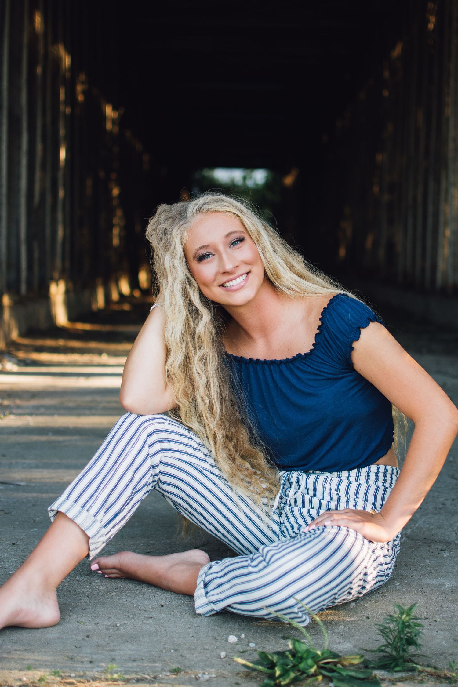 Person in navy top and striped pants relaxes during casual indoor photo session.