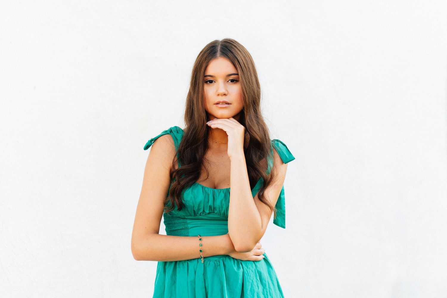 Fashion portraits in emerald green dress against white background.