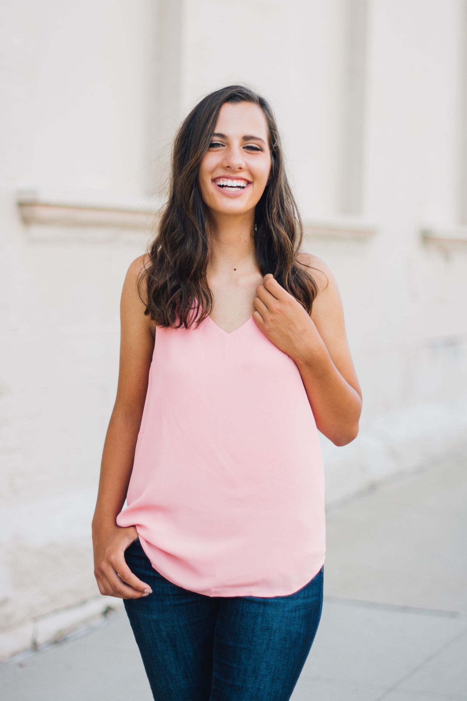 Indoor portraits wearing pink tank top against white wall background.