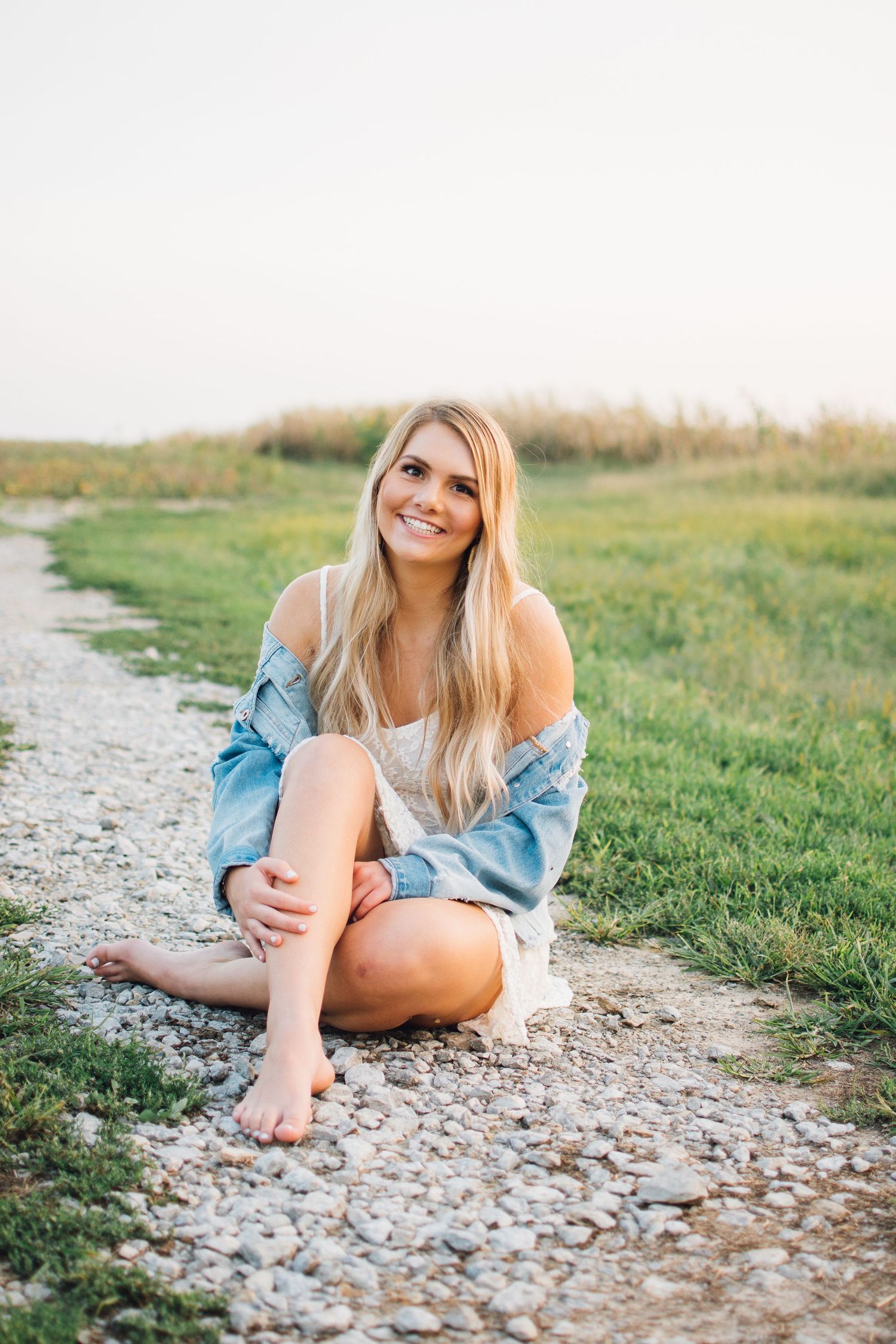 Casual outdoor portrait session on rocky path surrounded by green grass.