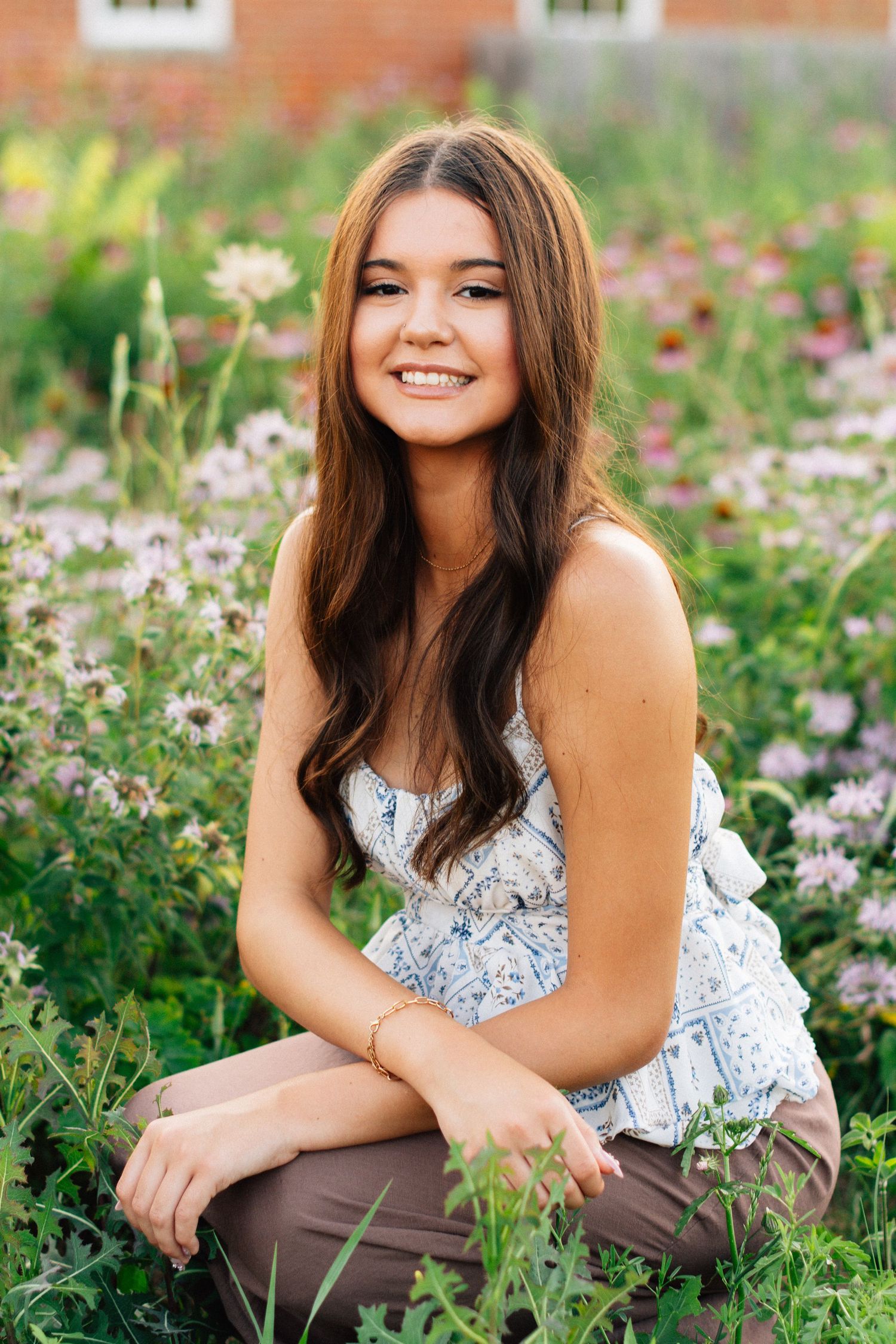 Outdoor portraits among purple wildflowers against a brick building backdrop.