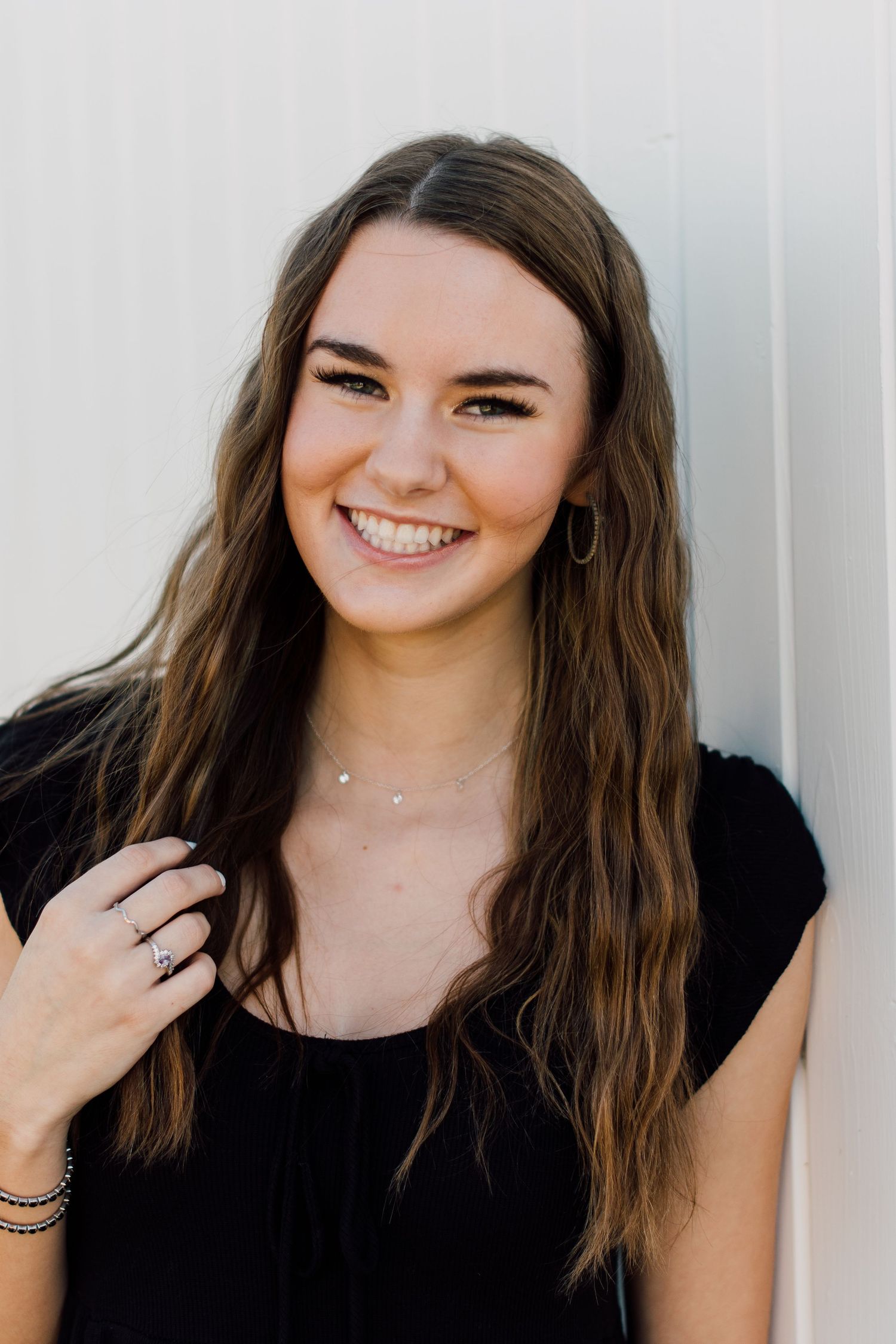 Portrait series in black top against white wall showing natural expressions.