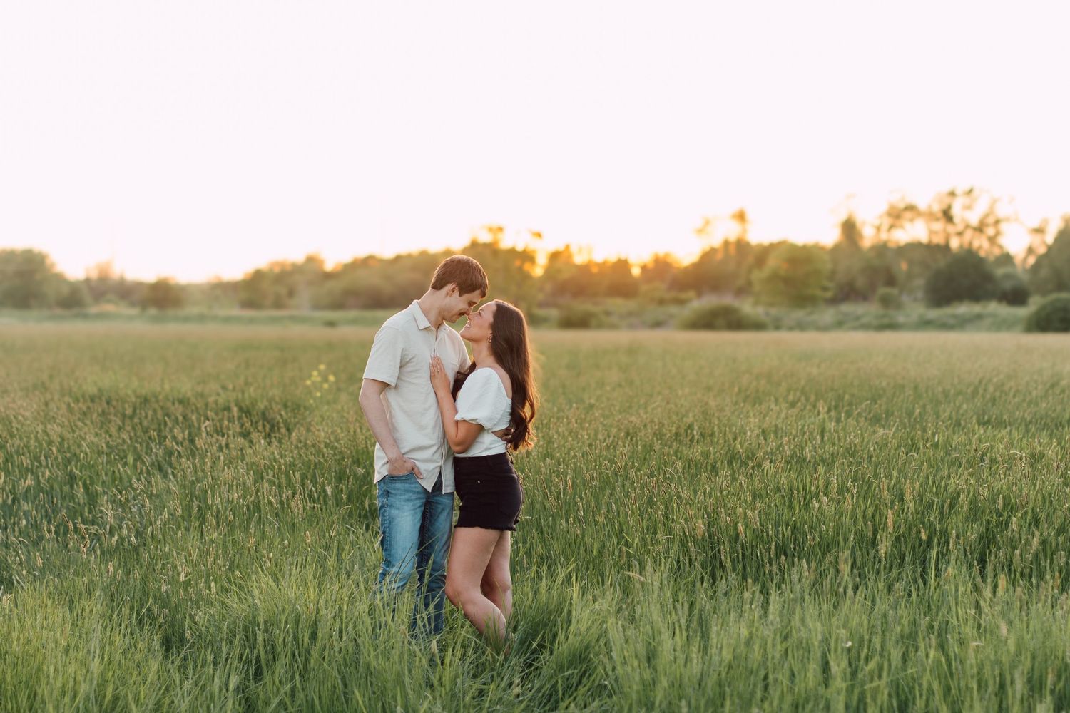 Engagement photoshoot in tall grass field at sunset.