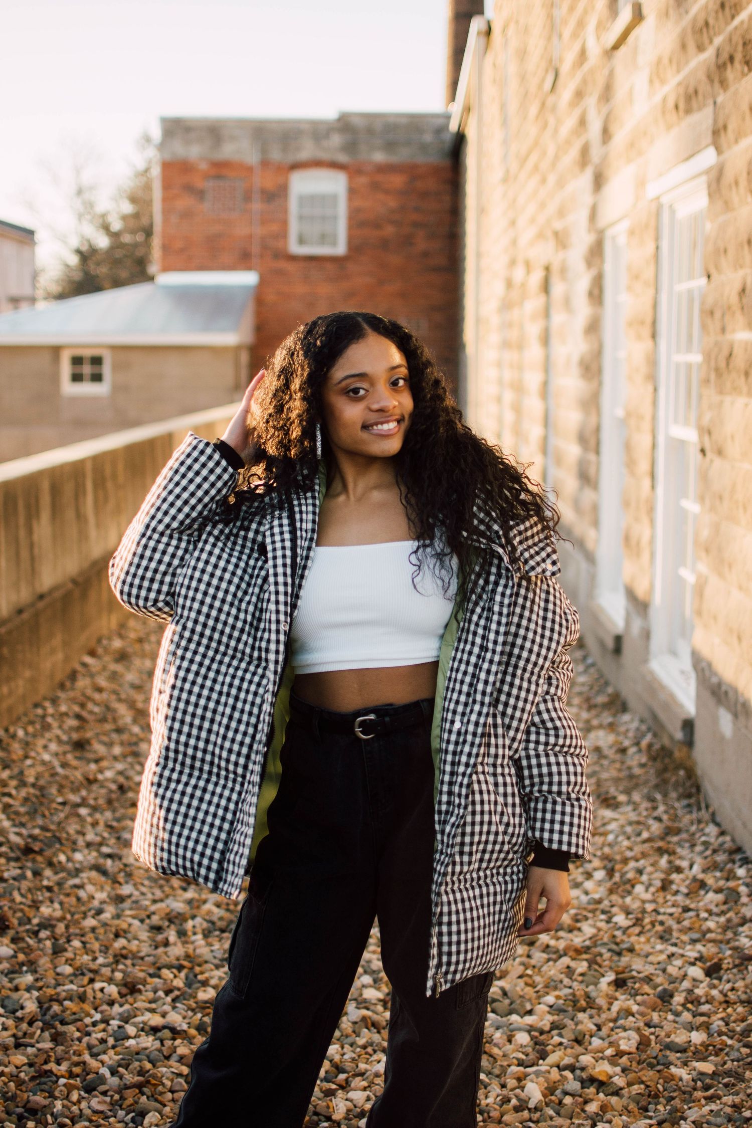 Two friends in casual outfits laugh together against brick wall backdrop.