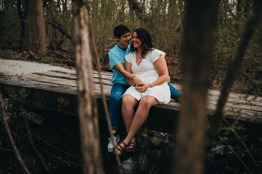 A romantic couple shares a tender moment together in a wooded forest setting.