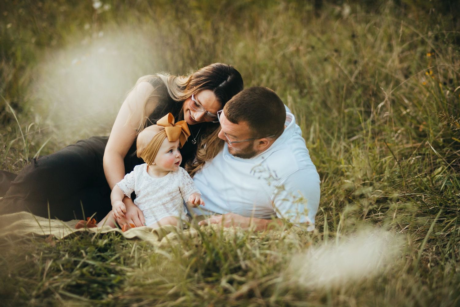 A family shares an intimate moment together while sitting in a sunlit grassy meadow on a warm afternoon. Family photos Terre Haute