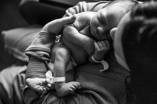 Black and white image of a sleeping newborn baby curled up by new mother. birth mom Family photos parke county