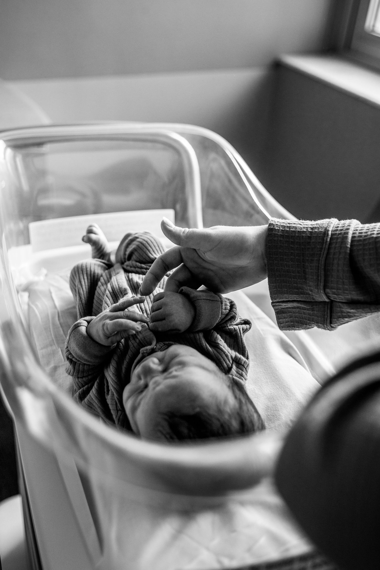 Union Hospital Terre Haute professional image of an infant in a hospital bassinet being comforted by a caretaker's hand local photographer