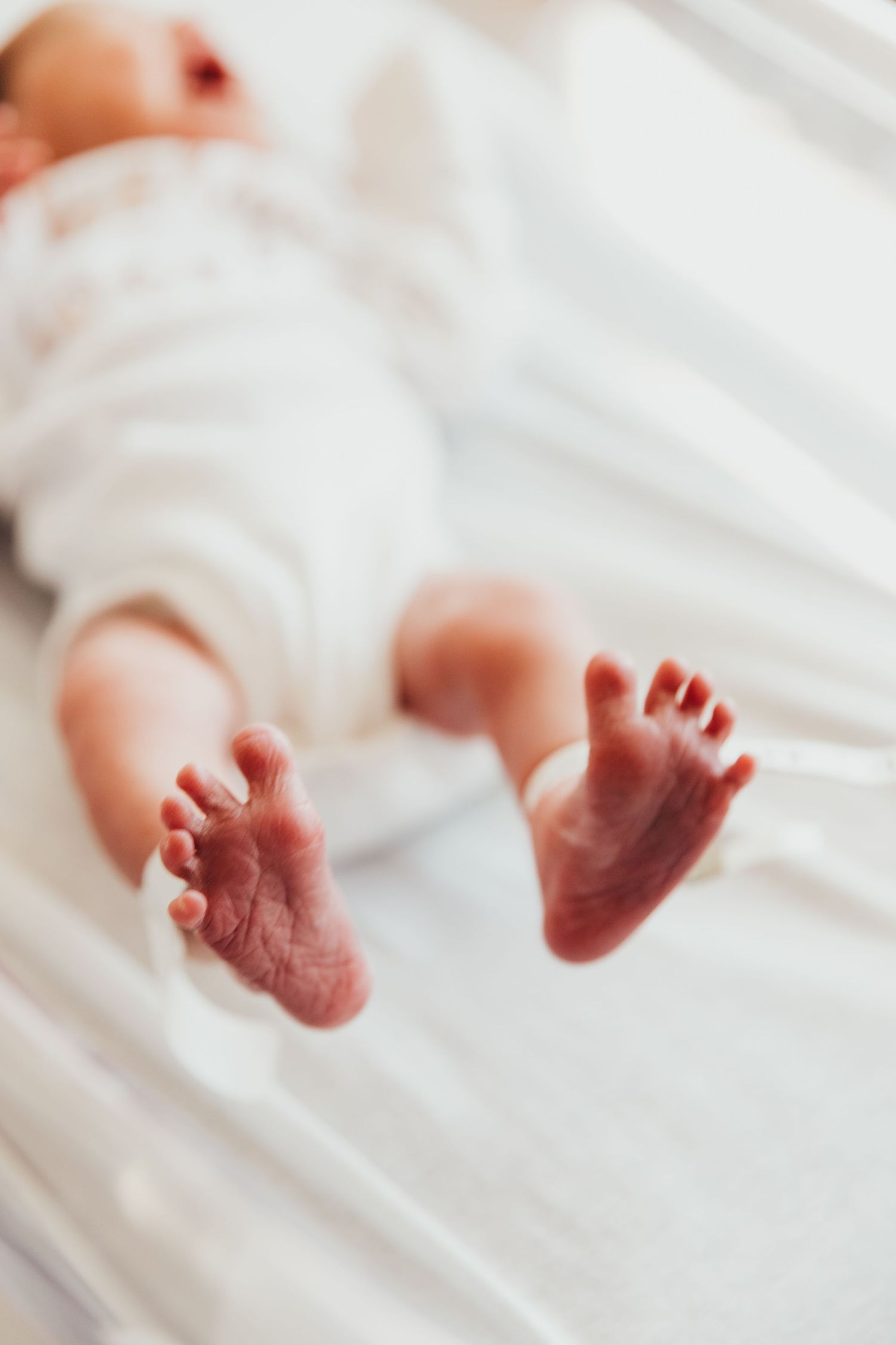Regional Hospital Terre Haute Newborn baby photos. Tiny newborn baby feet resting on white bedding in soft natural light. Vigo County