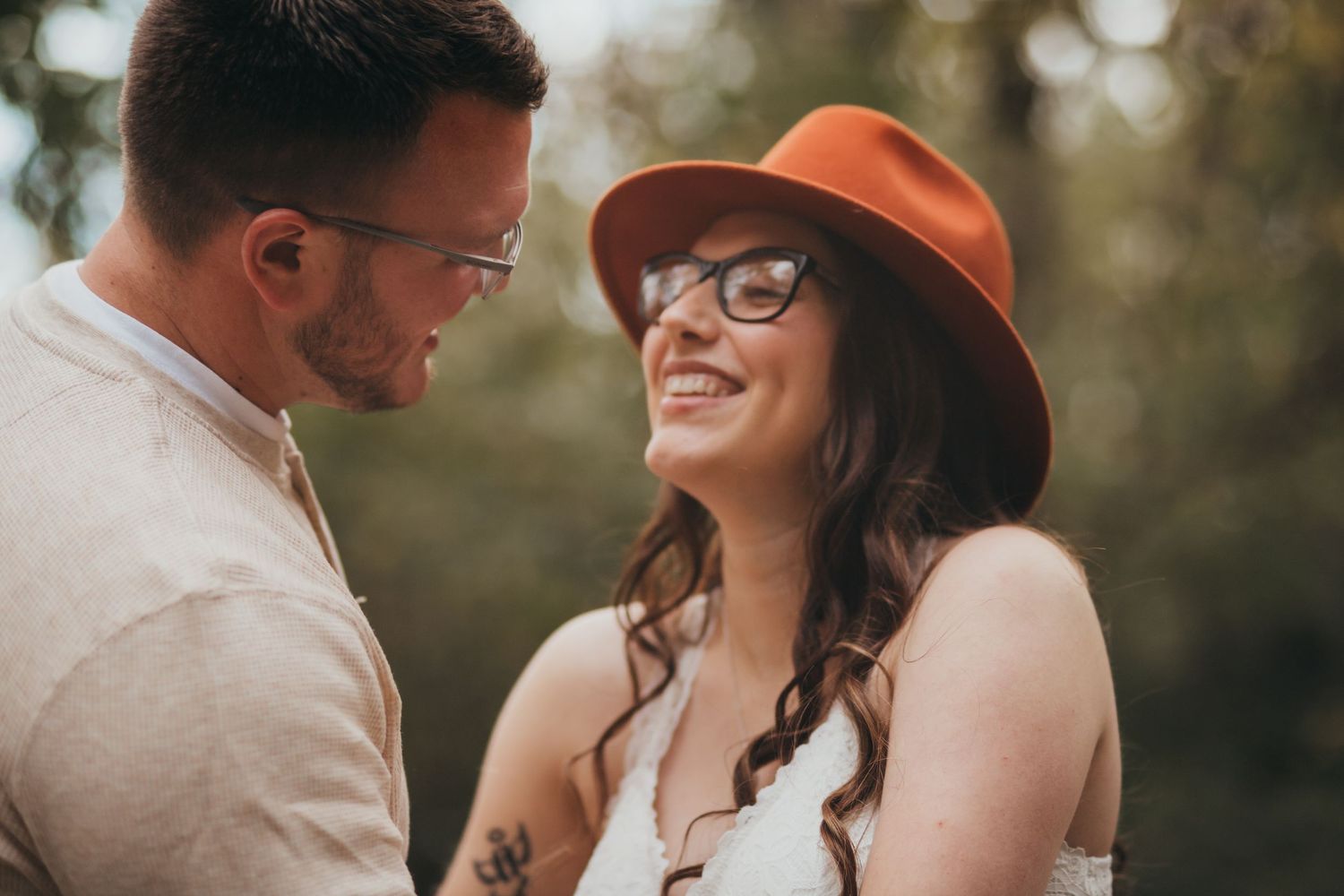 Couple enjoys intimate moment together in natural outdoor setting with autumn-colored leaves and warm sunlight.