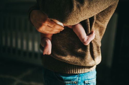 Close-up of hands in pockets of a brown sweater and blue jeans in moody lighting. Family photos north terre haute