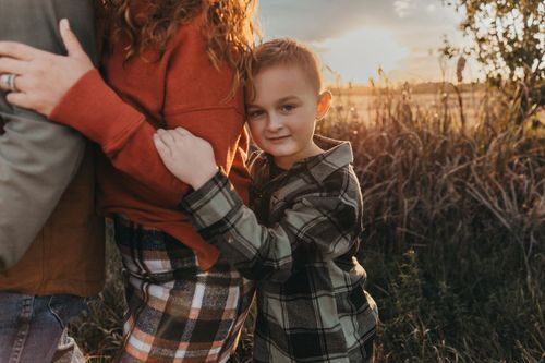 A family moment captured in a plaid flannel shirt against golden sunlit wheat fields during sunset. Children pictures vigo county