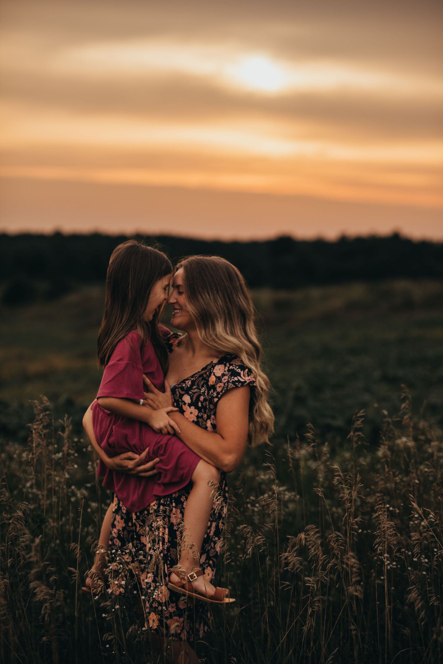 Silhouetted figures embrace in a dreamy golden sunset over a rural wildflower field.