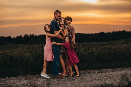 Family group hugging and laughing together on dirt path at sunset. Family pictures vigo county