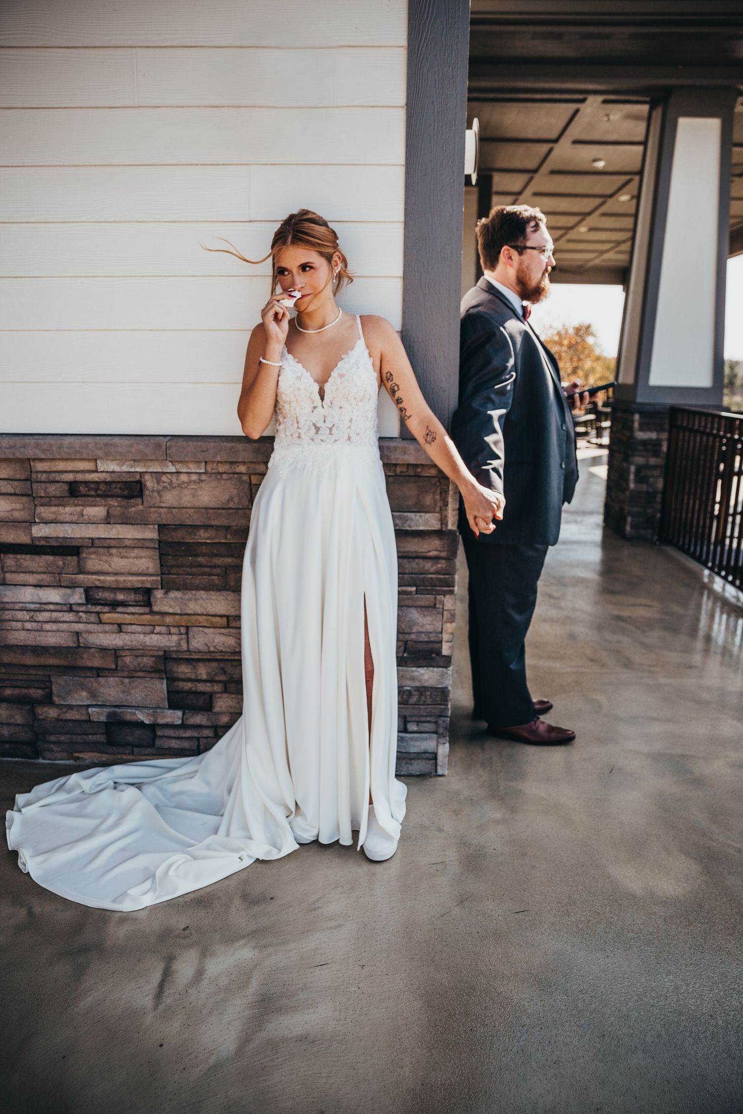 A wedding couple stands apart during their first look moment in an indoor venue with rustic stone walls. greencastle wedding photographer