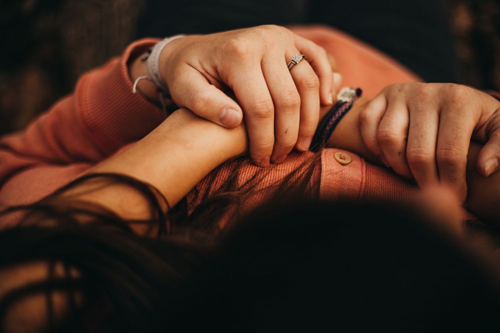 Close up shot of hands gently resting together in warm lighting.