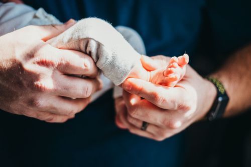 Hands carefully wrapping or unwrapping a white bandage or medical dressing. New Baby photos Clay County