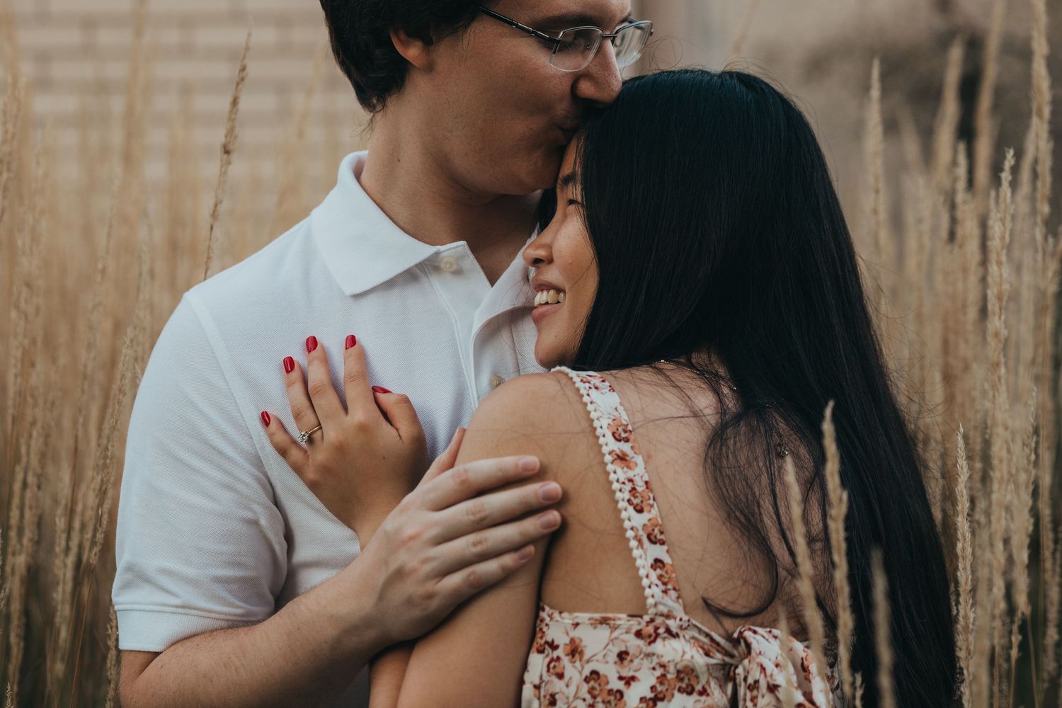 A couple embraces intimately in a field of tall grass during golden hour.