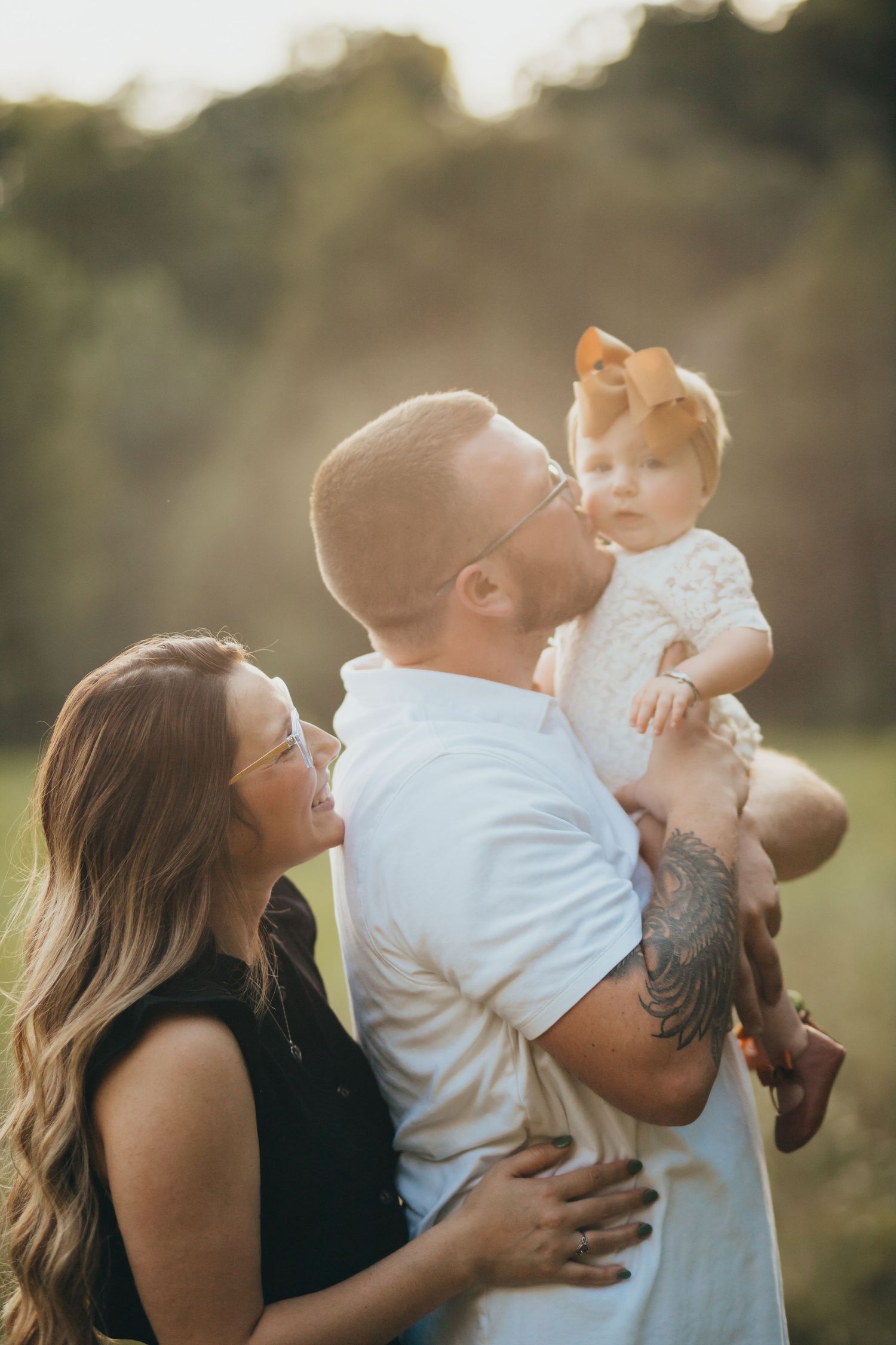 Family shares a tender outdoor moment at sunset in a natural setting.