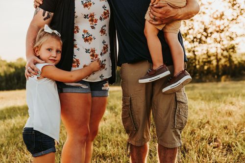 Cropped view of family members standing together in a sunlit field at golden hour. Family photos vigo county