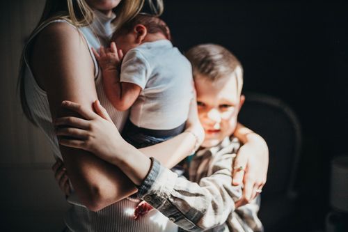 Family members embracing in a dimly lit room with emotional expressions. newborn photos Clay City professional photography baby and newborn