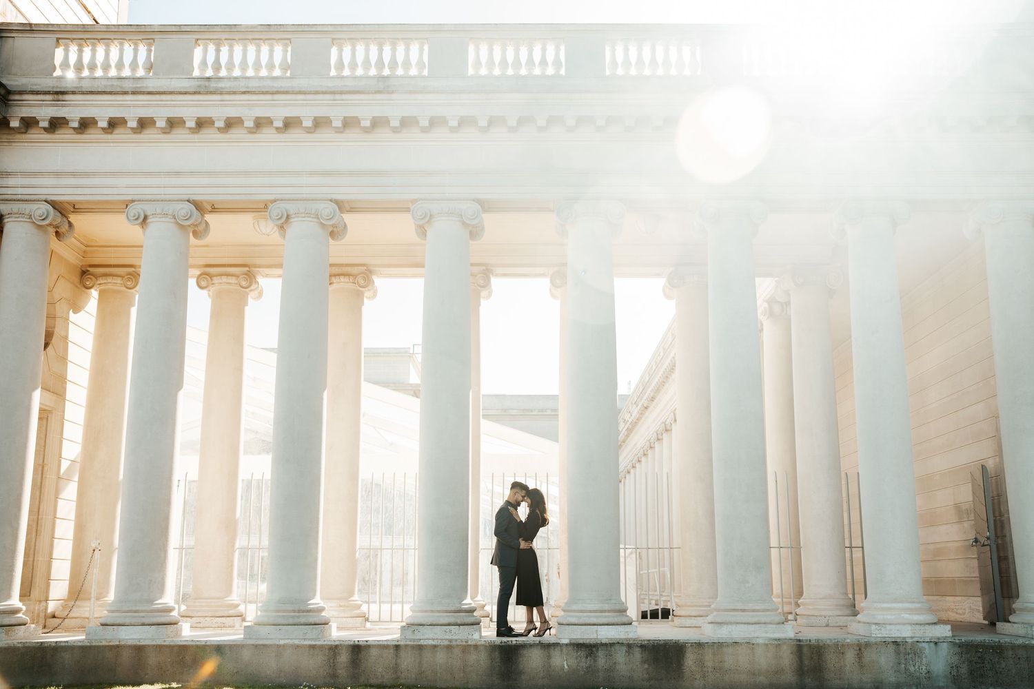 couple standing with their foreheads together amongst the columns at the legion of honor museum in san francisco during engagement photos