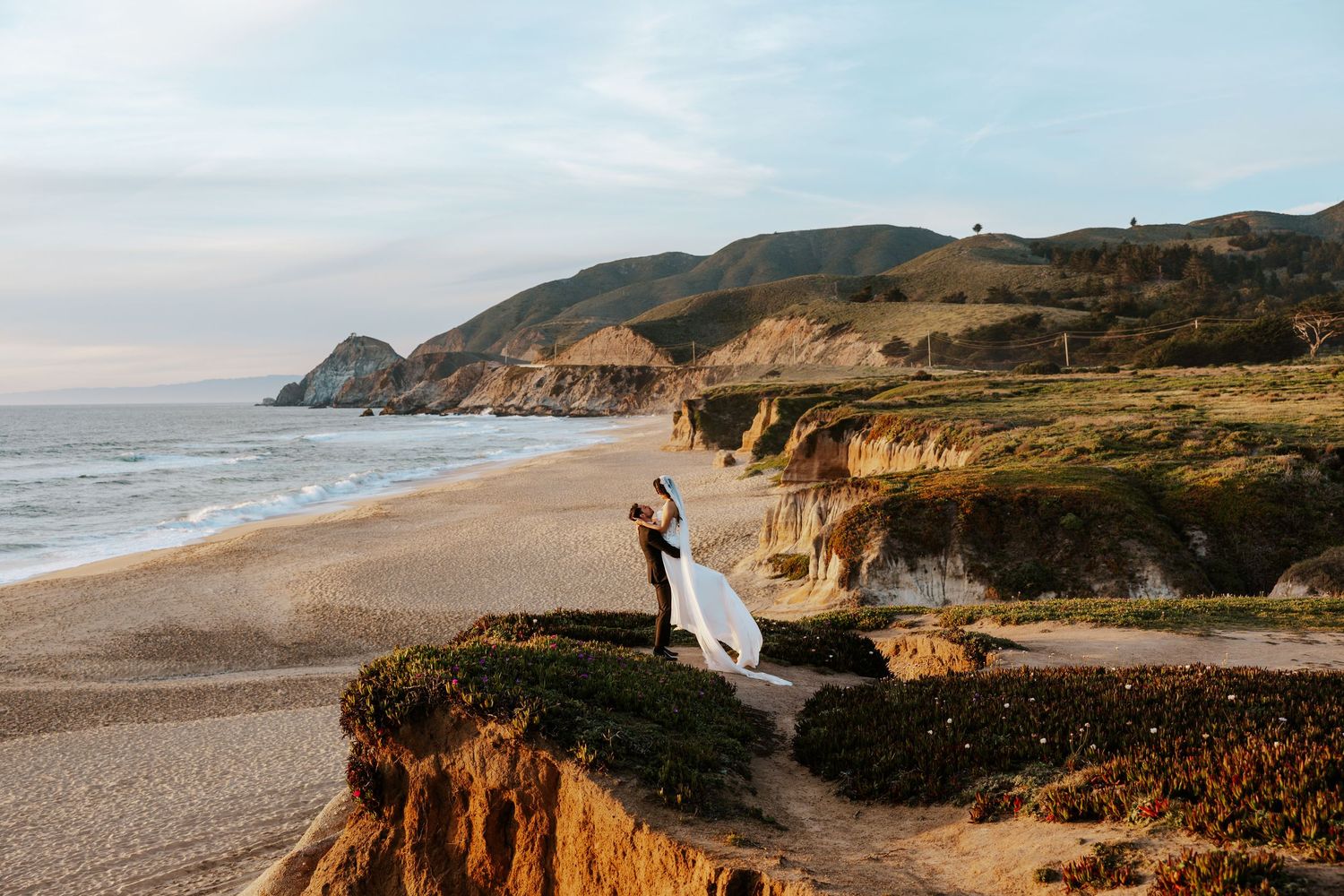 groom picking up his bride at Montara State Beach near Pacifica, California during their coastal san francisco elopement day