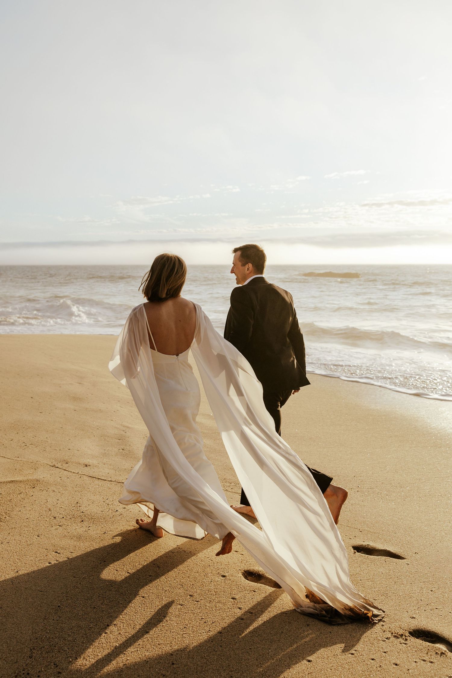 couple running along the Garrapata beach during beach elopement in big sur