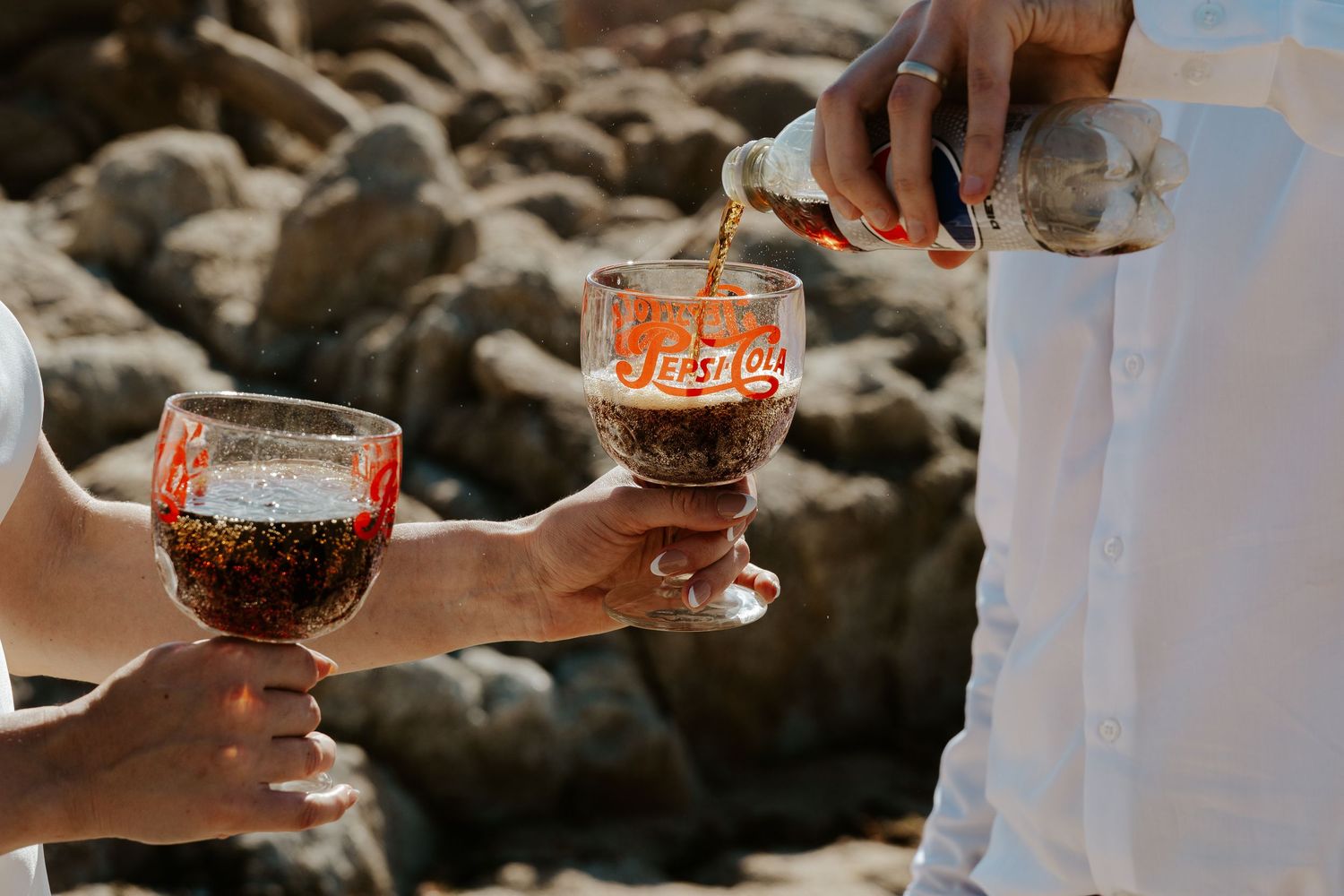 diet pepsi being poured into pespi glasses on beach elopement