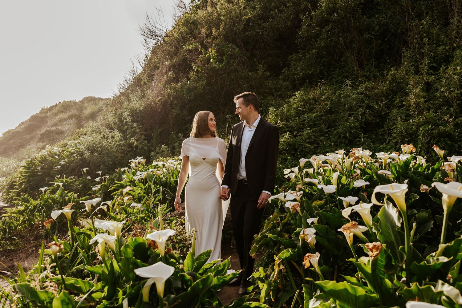 couple walking in a field of calla lilies during elopement day