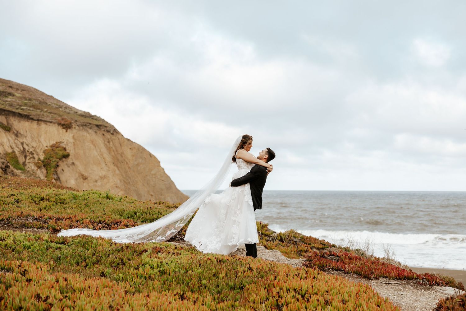 groom lifting bride up on the coast in the bay area during their candid elopement photos