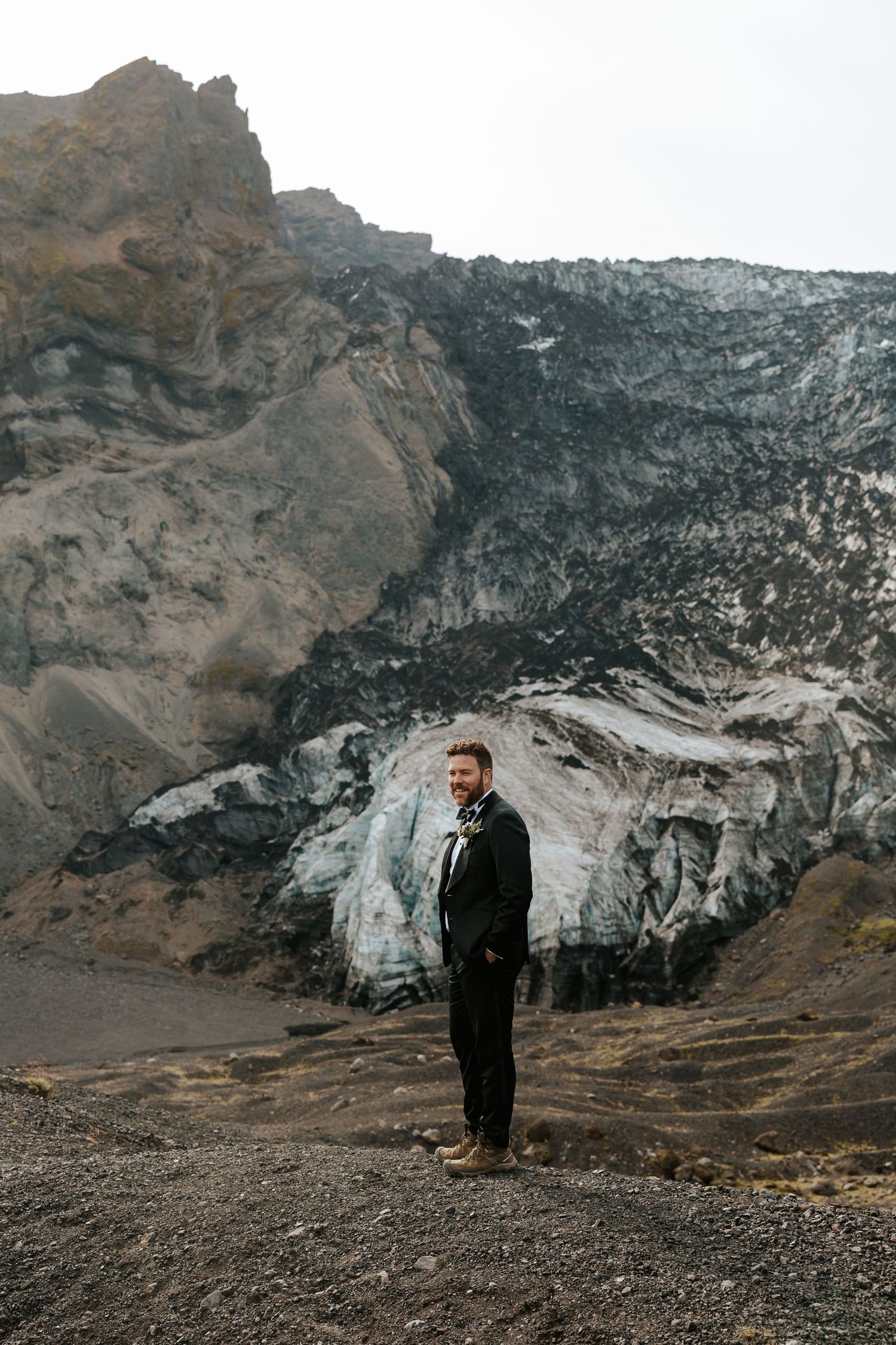 groom standing on a mountain waiting for his bride in Iceland