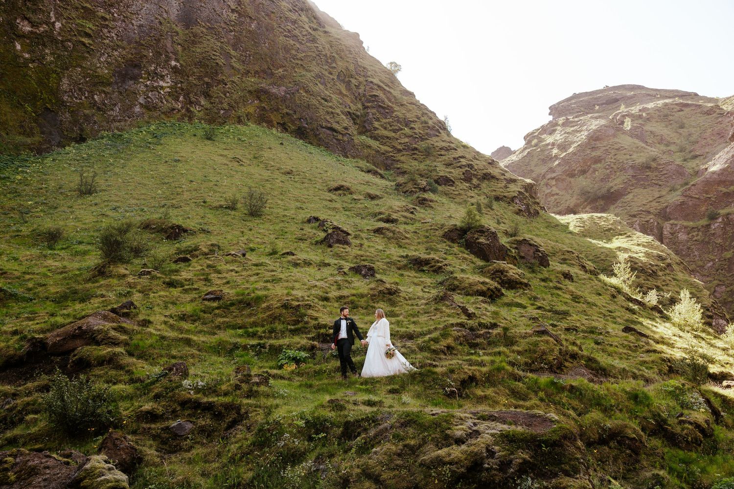 bride and groom walking through a green canyon in Þórsmörk (Thórsmörk), iceland