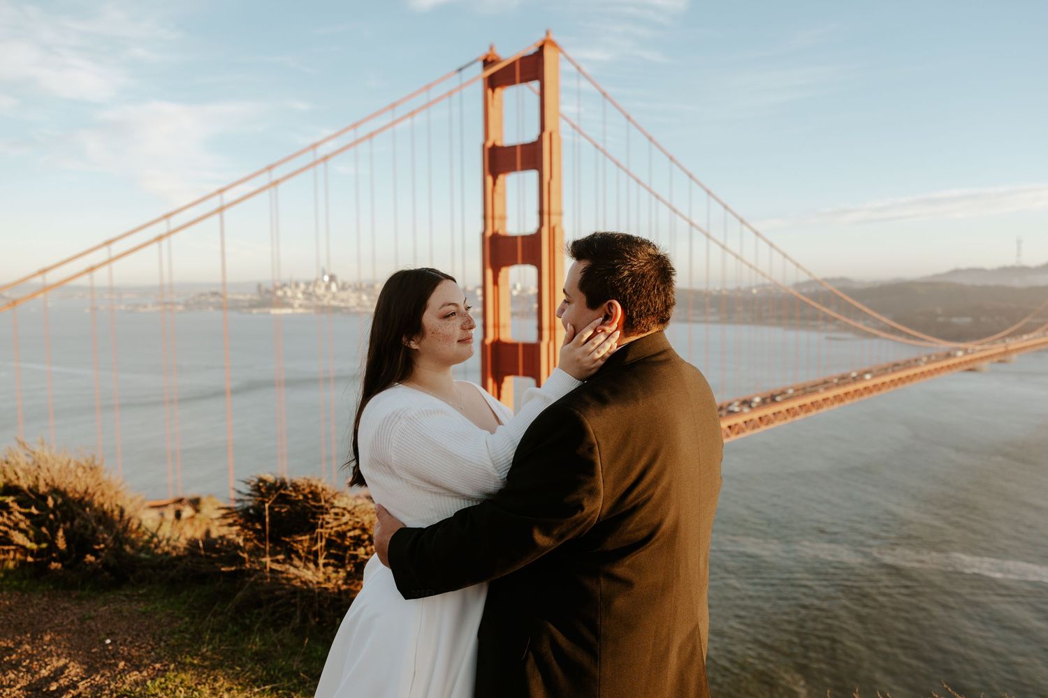 couple embracing each other with the golden gate bridge behind them at battery spencer on their san francisco elopement day
