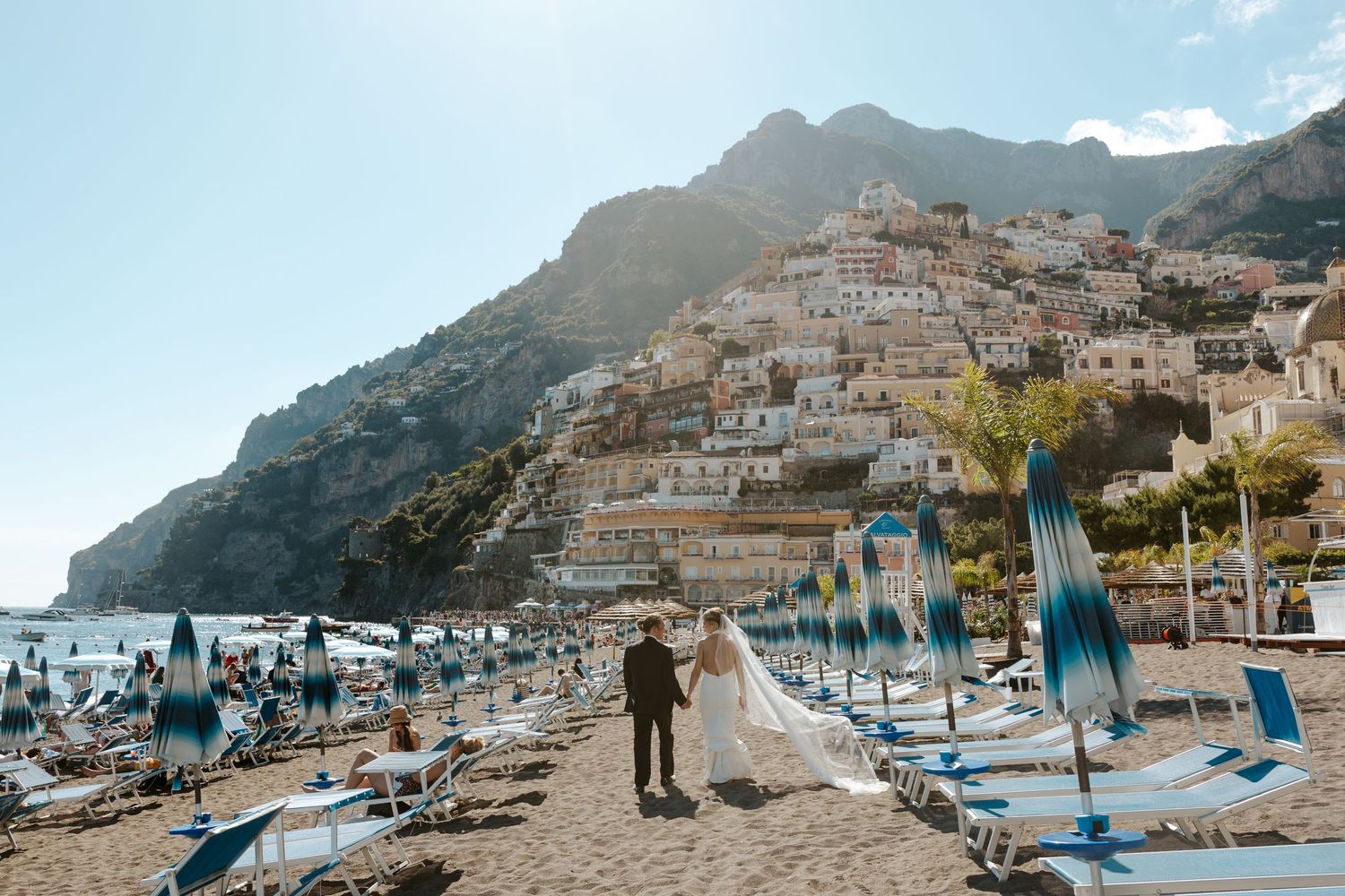 bride & groom walking on the beach in Positano with a view of the positano cliffside during amalfi coast elopement