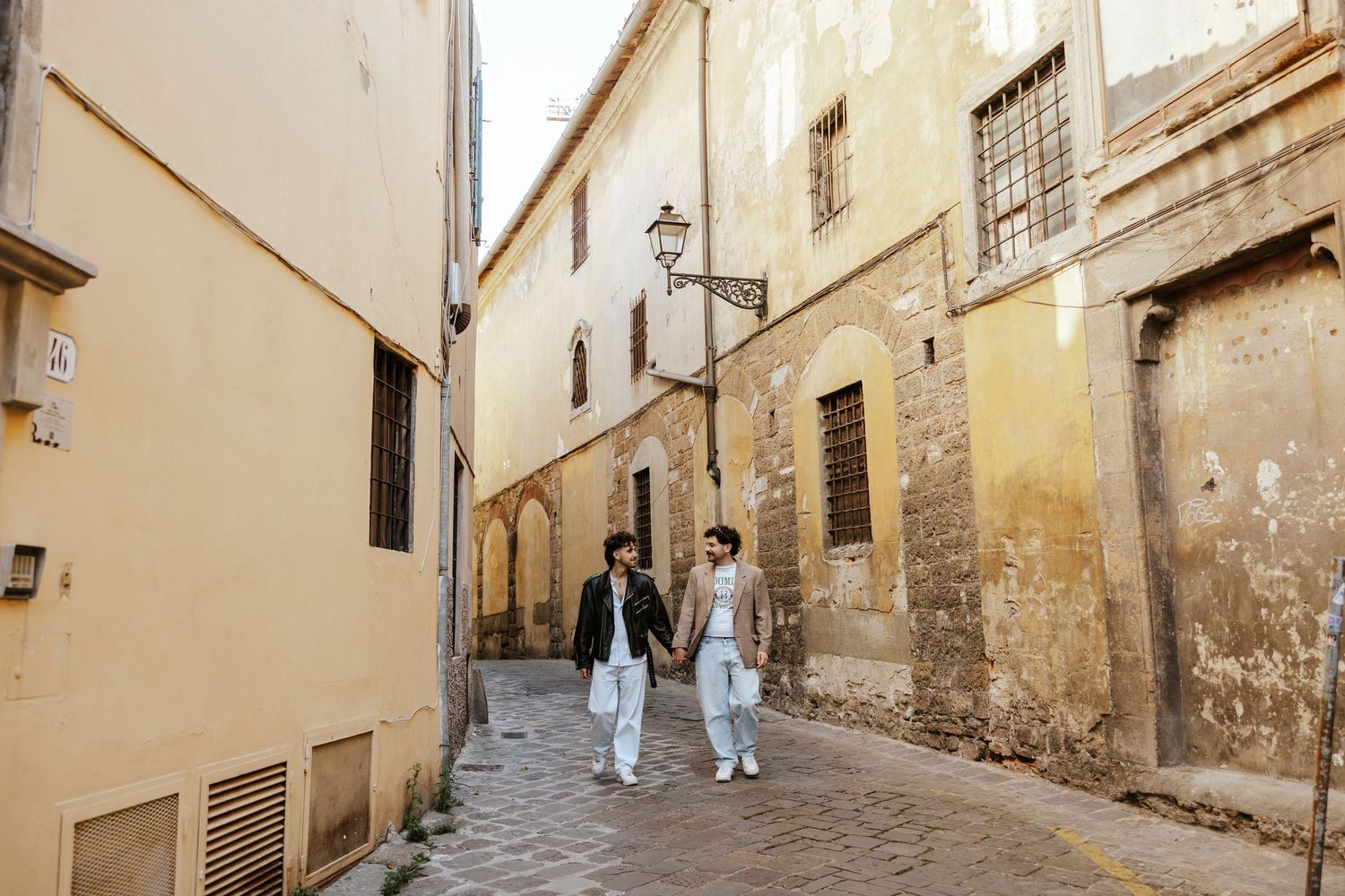 gay couple running through the streets in Siena on their elopement day