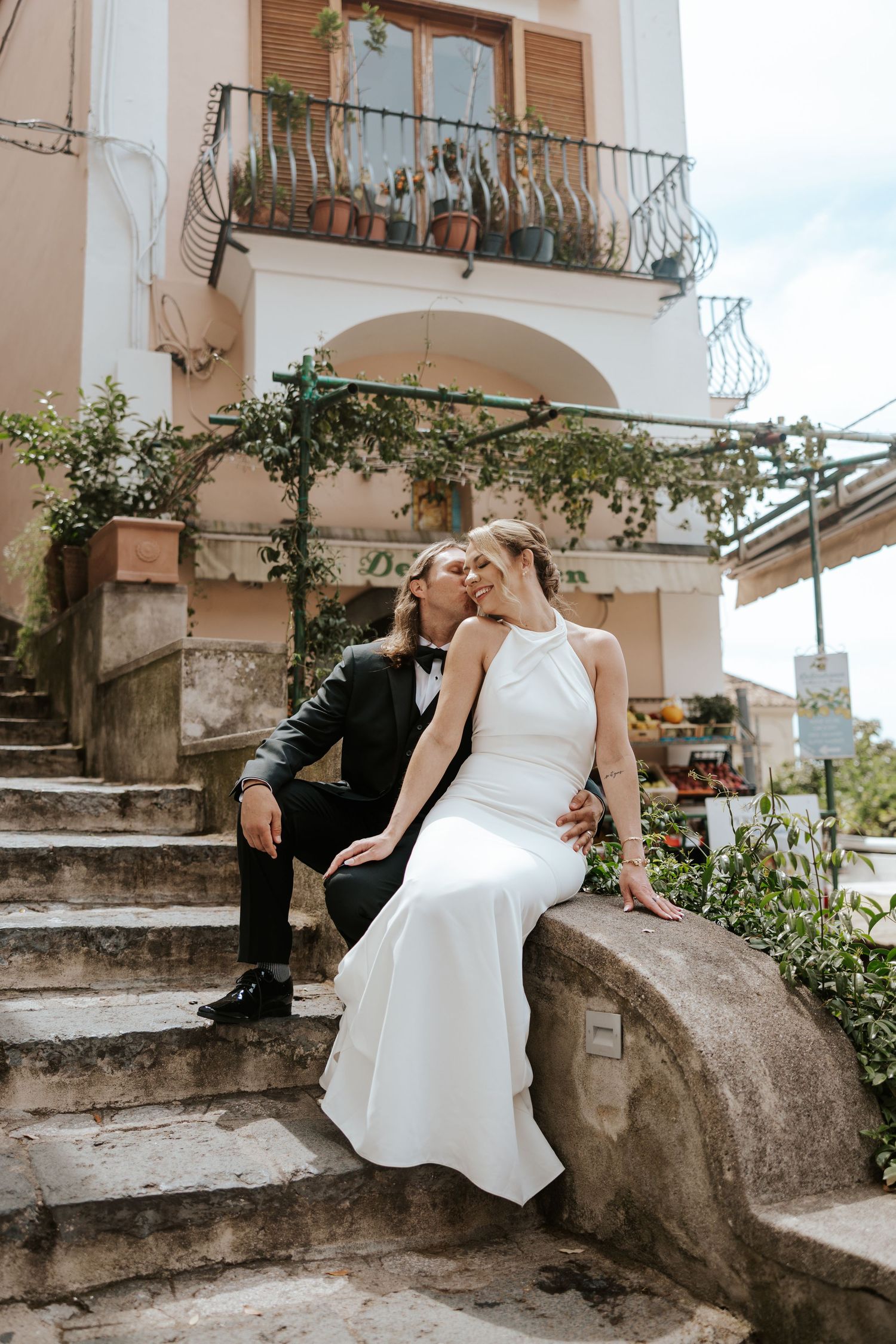 eloping couple sitting in front of pink delicatessen in Positano, Italy during amalfi coast elopement day