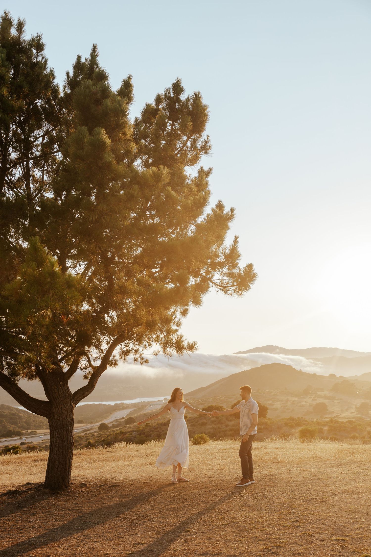 Bay Area engagement photoshoot at golden hour on a field overlooking a gorgeous view.