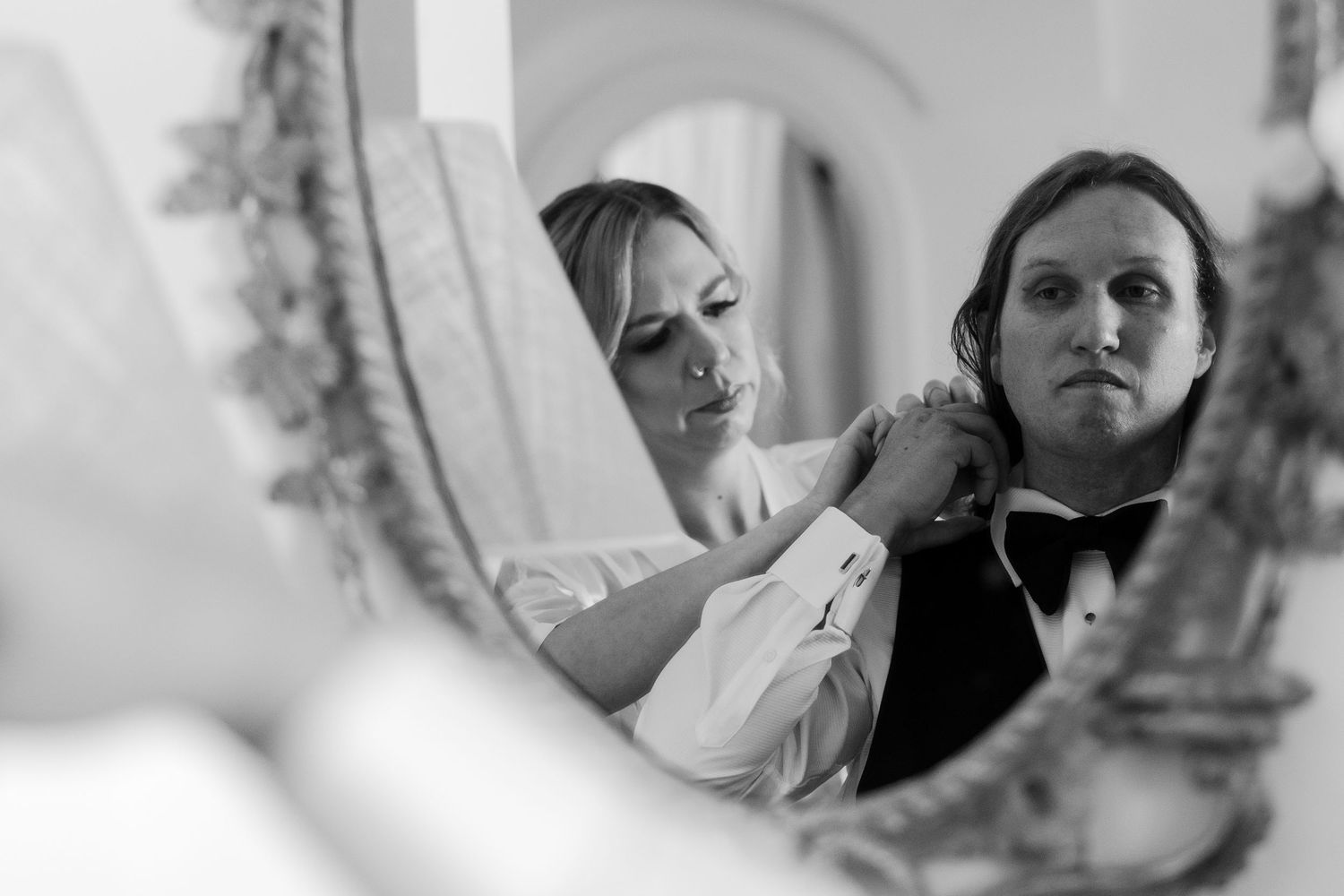candid of bride helping groom put on his bow tie for their Positano Elopement day