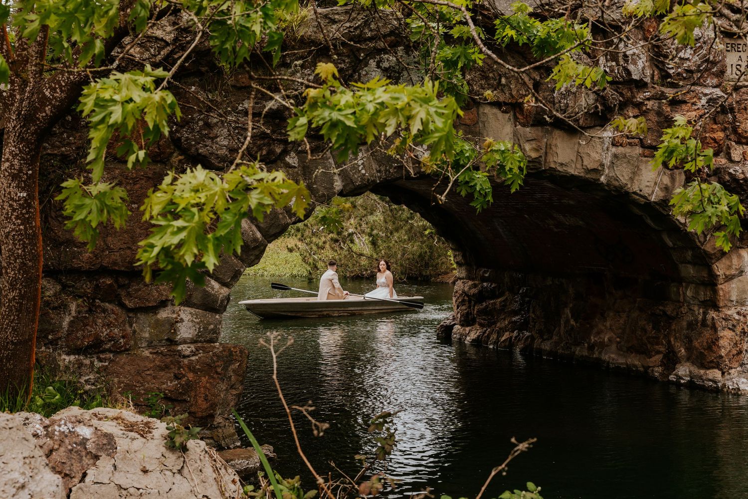 San Francisco elopement - a couple is on a romantic row boat in golden gate park under a stone bridge