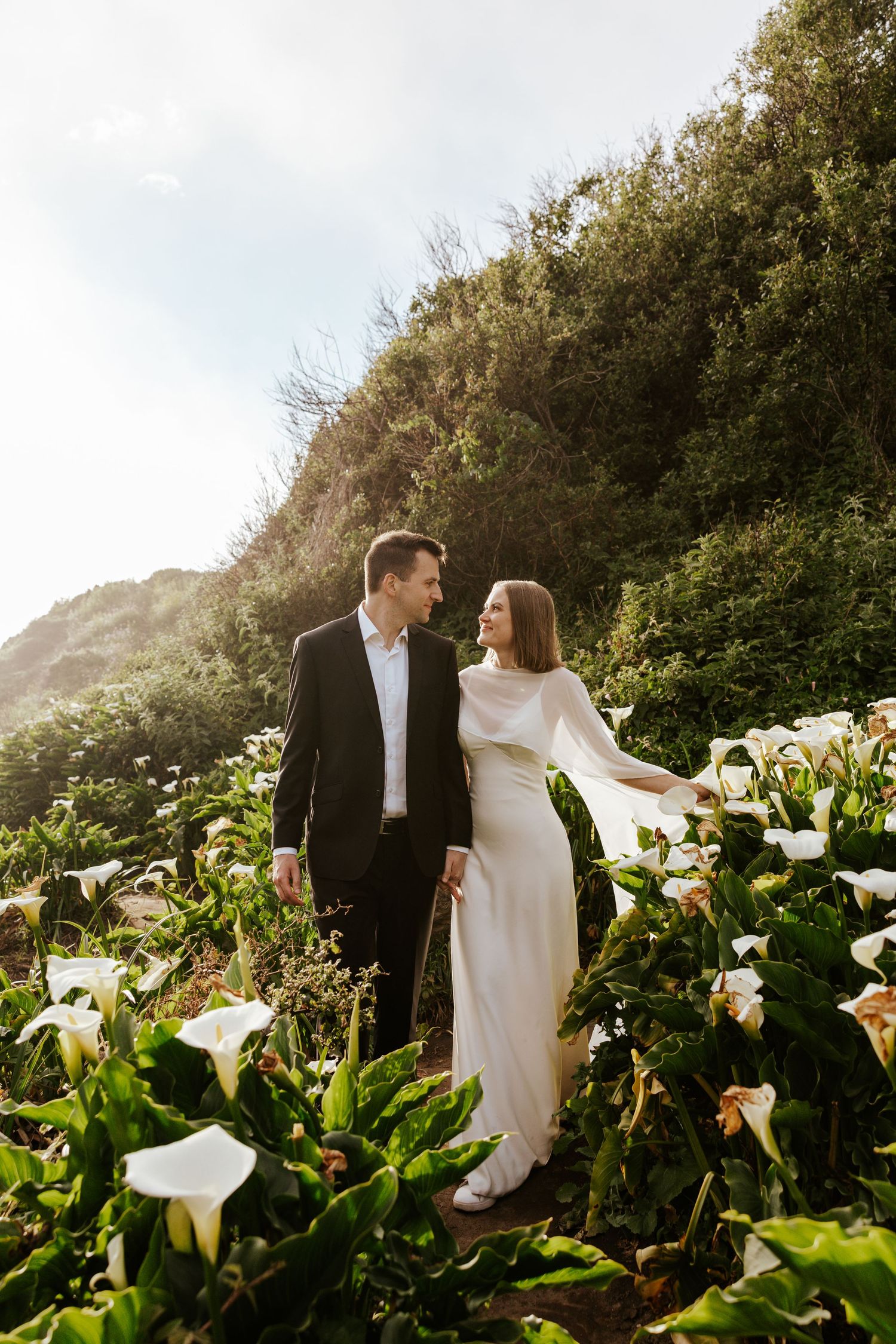 couple walking in a field of calla lilies during elopement day near big sur