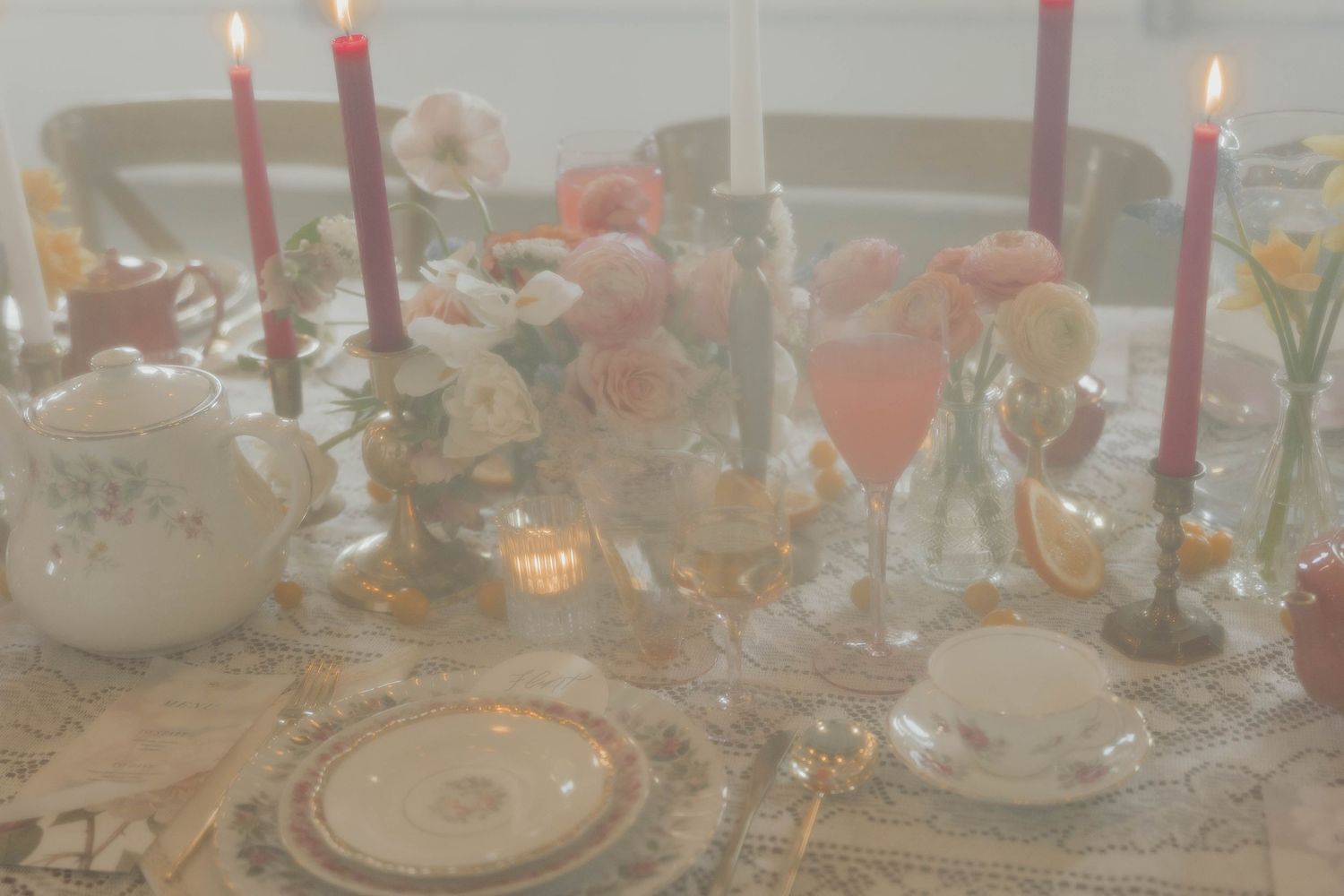 Romantic table setting with glowing candles, delicate flowers, and elegant dinnerware.