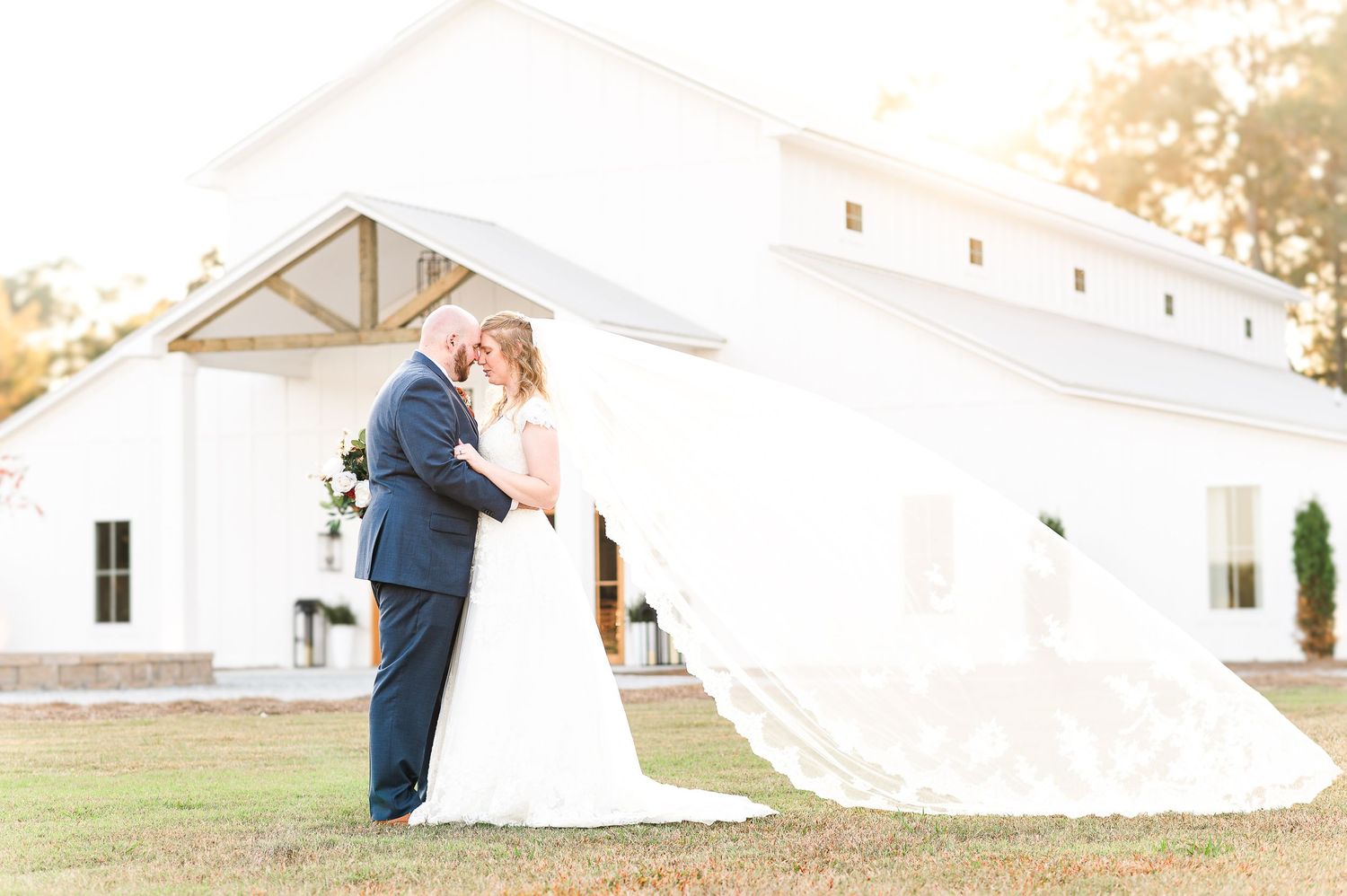 Bride and groom in front of white barn venue