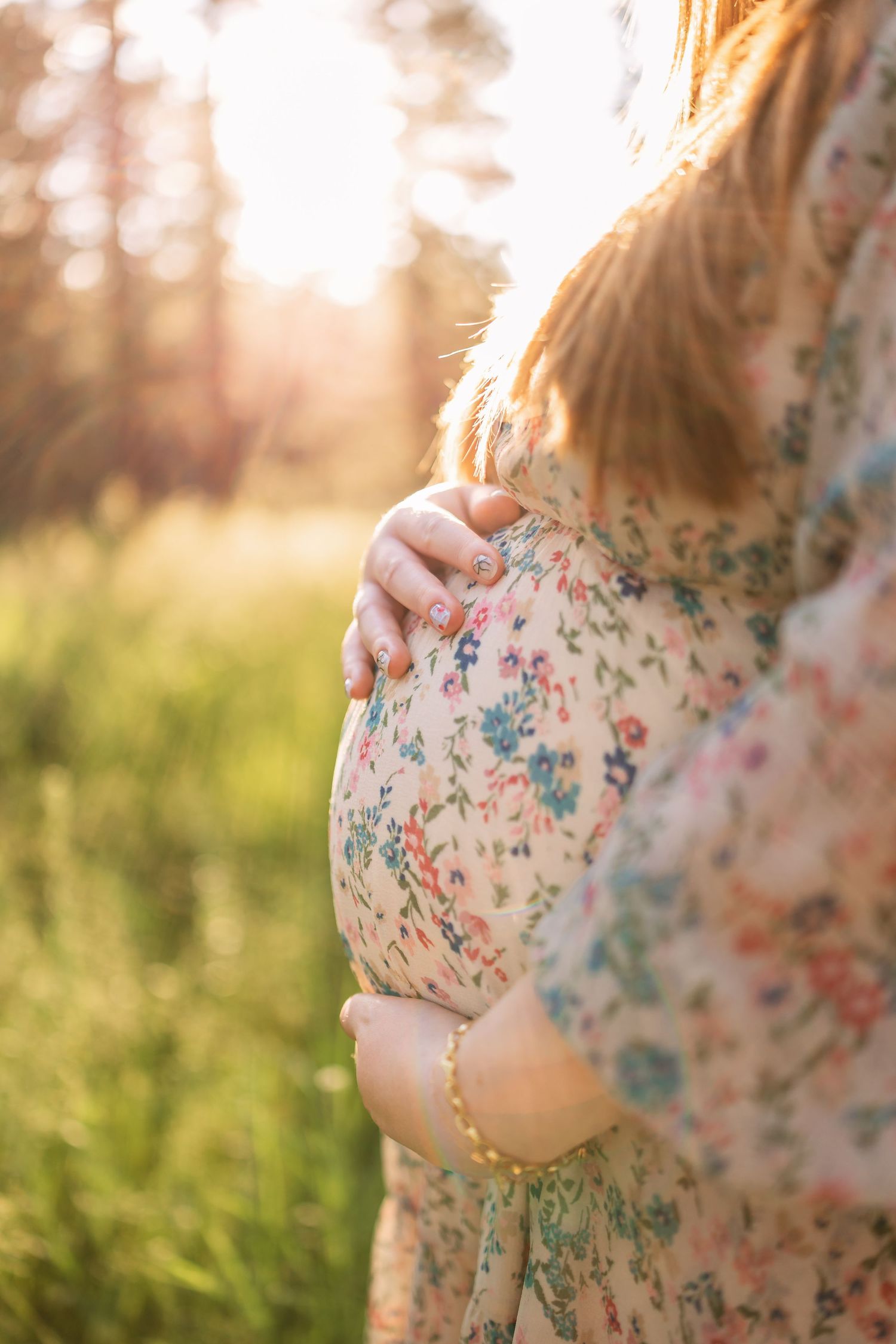 Close-up view of hands touching floral patterned fabric in warm golden sunlight at sunset.